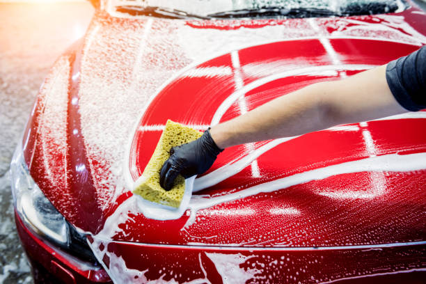 istock Worker washing red car with sponge on a car wash 1285790116
