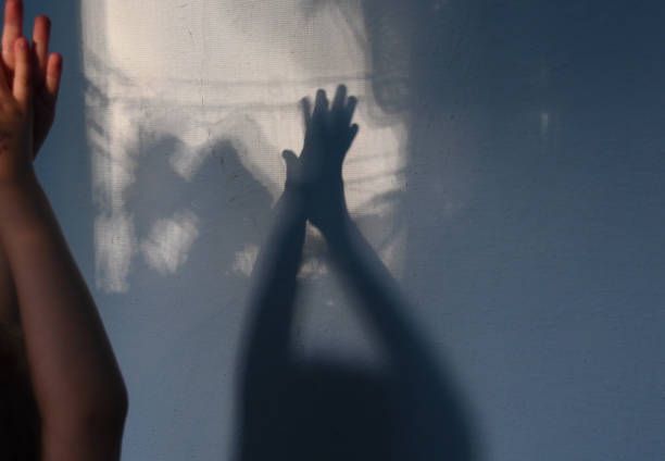 istock Defocus shadows of kid clapping hands on stucco wall surface with copy space. Halloween concept 1285790212
