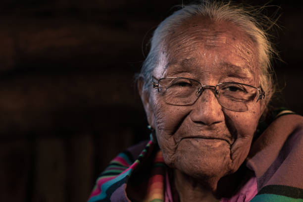 ein fine art portrait einer lächelnden älteren navajo großmutter sitzt in ihrem authentischen hogan in monument valley, arizona - navajo american culture indigenous culture women stock-fotos und bilder