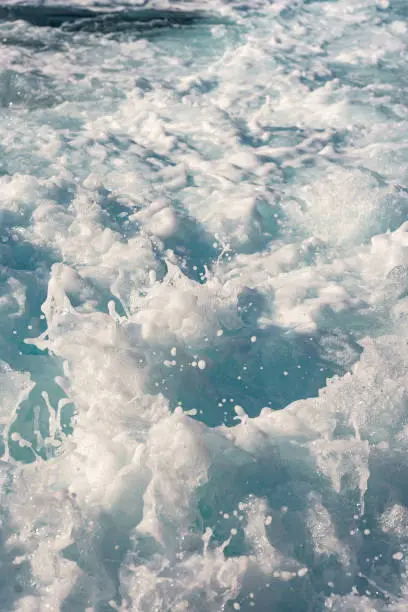 Water surface background. Blue sea water splashes with sun reflections. Ripples of water in the.