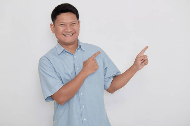 istock Asian man smiling with his finger pointing 1285795186