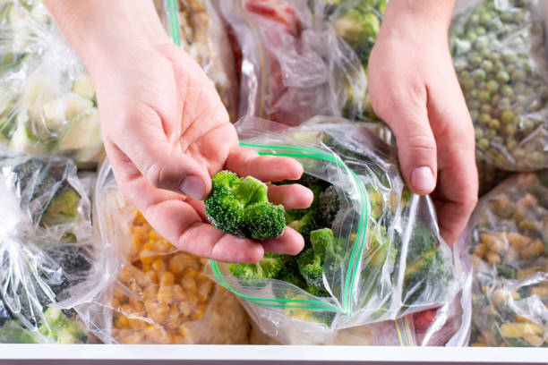 istock Frozen broccoli in hand, closeup. Frozen vegetables in a plastic bag in refrigerator 1285797819