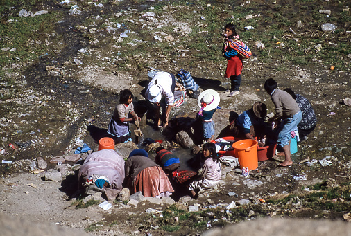 Puno, Peru - aug 1994: a large group of Peruvian peasants and women flock to a pool of water where they wash their clothes.