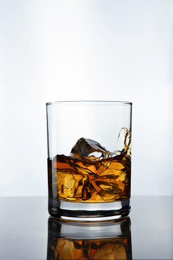 Whiskey glass, bottle and cigar on black glass surface