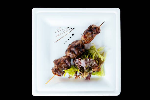 istock Pig kebab on a stick on a plate with green salad 1285806307