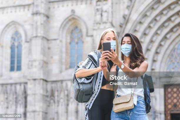 Caucasian And Indian Female Friends Using Smart Phone To Take Themselves A Picture With Barcelona Cathedral On The Background - Fotografias de stock e mais imagens de Máscara de proteção