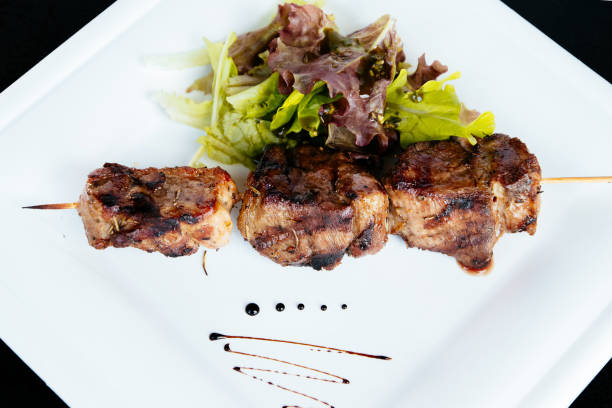 istock Pig kebab on a stick on a plate with green salad 1285807451