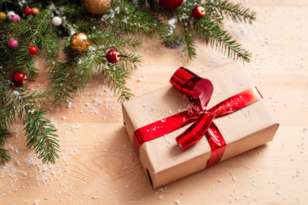 istock Christmas present near decorated fir tree on wooden table. 1285812568