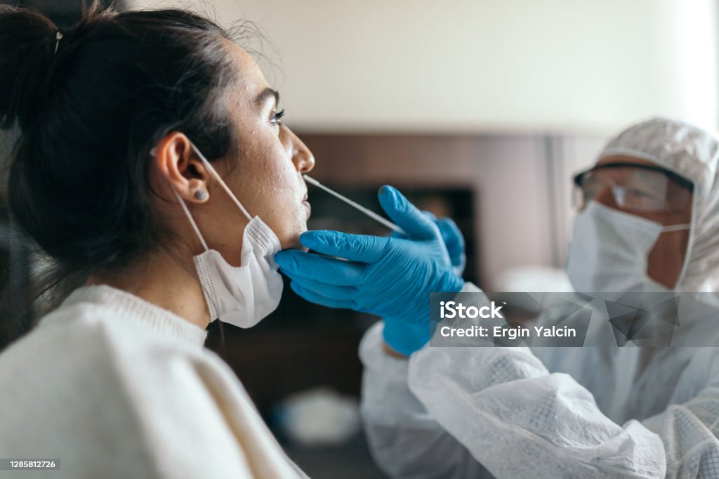 Doctor in protective workwear taking nose swab test from young woman Coronavirus Stock Photo