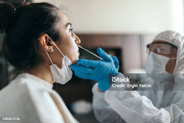 Doctor In Protective Workwear Taking Nose Swab Test From Young Woman Stock Photo - Download Image Now