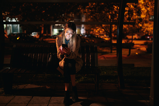 Female sitting on bench and using cellphone