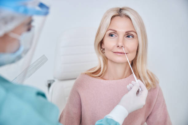 Nurse inserting the swab into the woman nostril Experienced lab technician collecting the sample of mucus from the female patient nose for analysis medical swab stock pictures, royalty-free photos & images