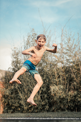 Young boy jumping happily jumping on a trampoline while at home