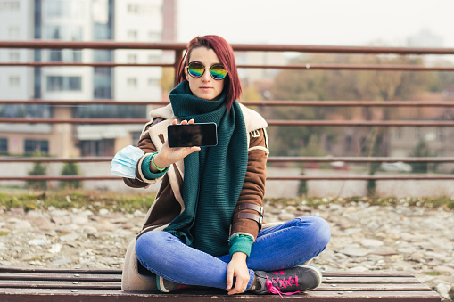 Young woman using phone in city park stock photo