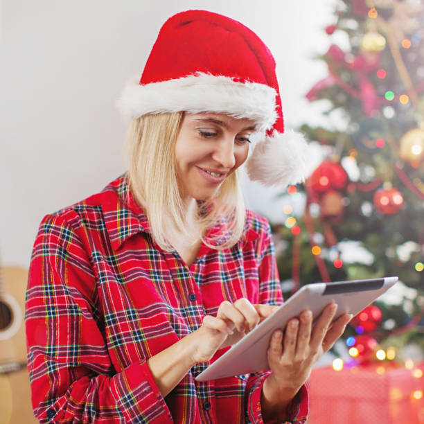 istock Woman using tablet in front of christmas tree 1285818122