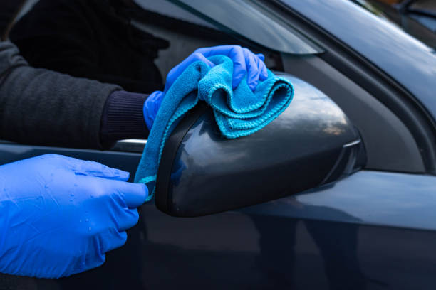istock A woman's hand in a blue glove washes the car mirror with a blue rag. 1285819084