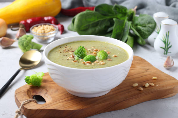 вегетарианский крем-суп с брокколи, шпинатом и цуккини в белой миске на сером фоне. крупным планом. - soup zucchini spinach cream стоковые фото и изображения