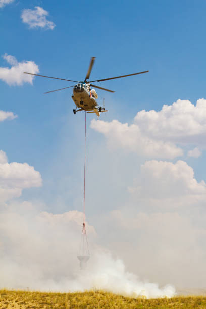 istock Firefighting helicopter with fire bucket flies 1285822271