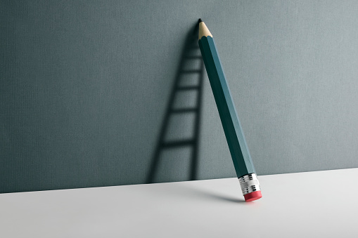 A pencil leaning against the wall. Ladder shade reflect on the wall.\nCopy space for your text.