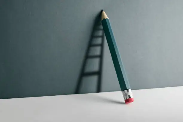Photo of A pencil leaning against the wall. Ladder shade reflect on the wall.