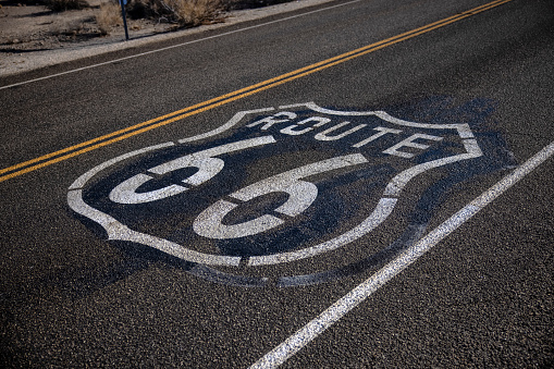 A vintage Kansas 66 highway sign painted on an asphalt highway in a rural area