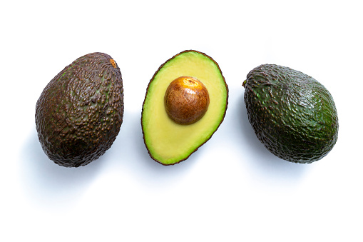 Three avocado fruits in a row one half cut isolated on white background with shadow