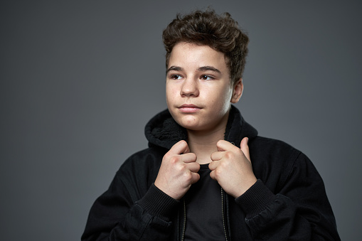 Closeup portrait of a trendy teenage boy over gray  background