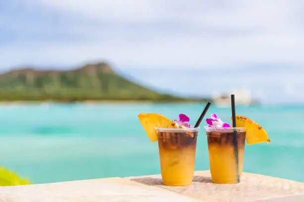 Photo of Hawaii mai tai drinks on waikiki beach bar travel vacation in Honolulu, Hawaii. Famous hawaiian drink cocktails with view of ocean and diamond head mountain, Hawaii tourist attraction