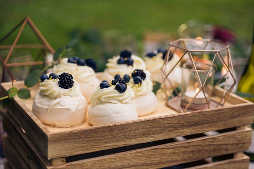 Mini pavlovas with mascarpone filling and berries at a relaxed, rustic outdoor wedding reception.