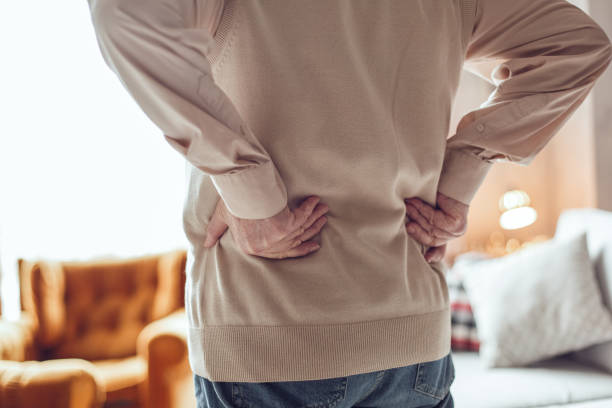 istock Senior man alone standing at library touching small of back close-up 1285833789