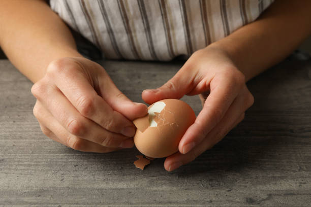 istock Woman peeling boiled egg on gray background 1285833859