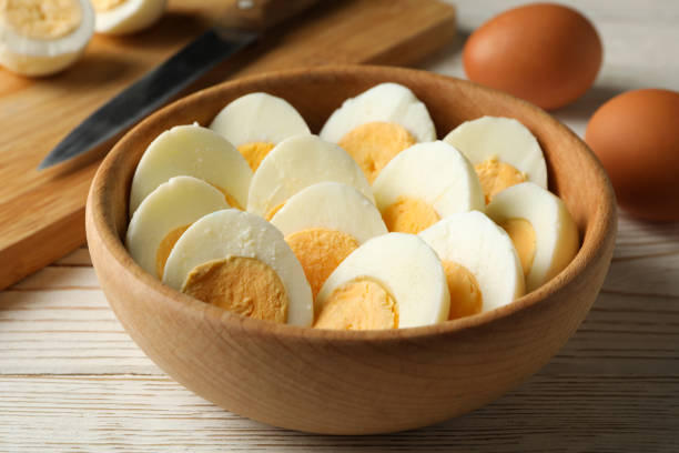 istock Board and bowl with boiled eggs and knife on white wooden background 1285834768