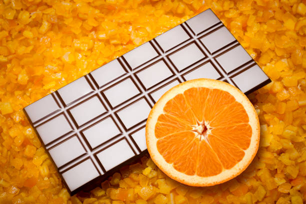 Close-up of chocolate bar and an orange slice on candied orange fruit.