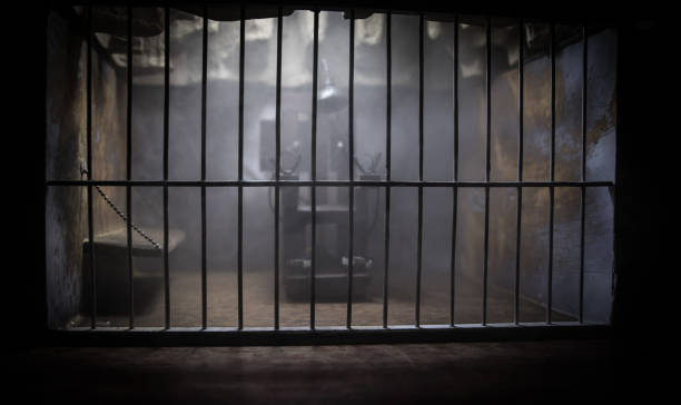 Jail or prison cell. Obsolete gray grunge concrete room. Old prison miniature. Execution concept Execution concept. Death penalty electric chair miniature in selective focus inside old prison. Old prison bars cell lock. Creative artwork decoration. Electric chair scale model in the dark torture photos stock pictures, royalty-free photos & images
