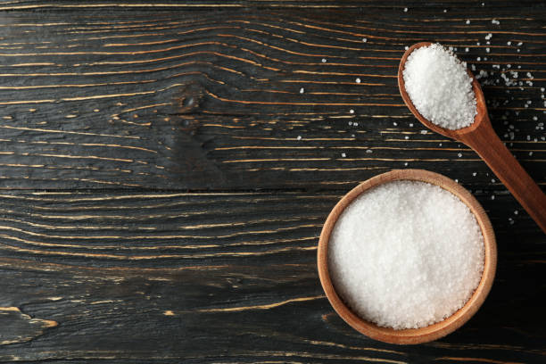 istock Spoon and bowl with salt on wooden background 1285836164