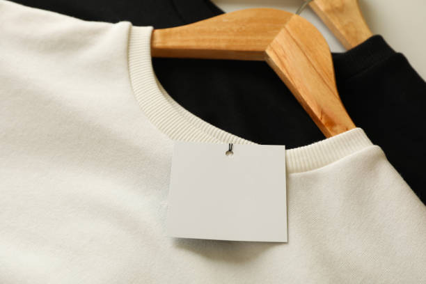 istock Hangers with stylish sweatshirts and blank tag, close up 1285838556