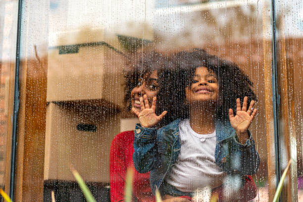 istock Mom and daughter look out the window on a rainy day while moving 1285840186