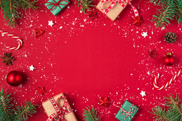 istock Christmas composition on red background. Frame made of gifts, fir tree, candy, decorations. Flat lay, top view 1285843098