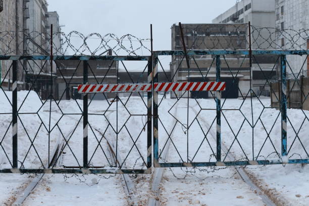 istock Closed factory gate with barbed wire. Winter, daylight. 1285845195