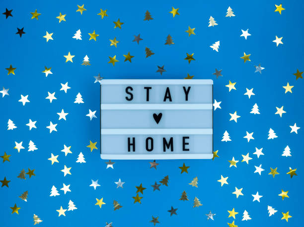 istock Light box with Stay home quote on a blue background with confetti. Christmas quarantine. 1285845381