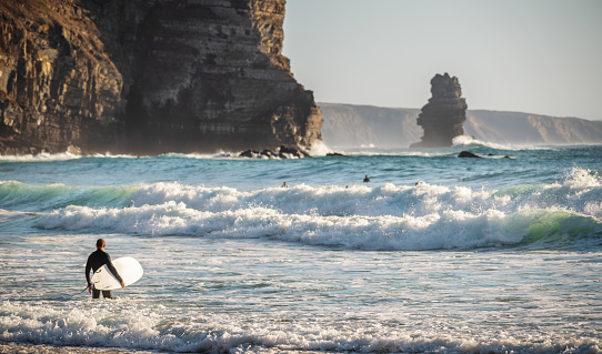 Aljezur, Portugal - October 3, 2020: Surfers going for water surfing at Praia da Arrifana Beach, Aljezur, Vicentine Coast, Algarve, Portugal