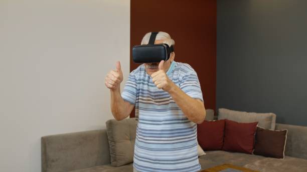 istock Happy senior man using virtual reality headset glasses, trying to touch something, watching 3D video 1285847338