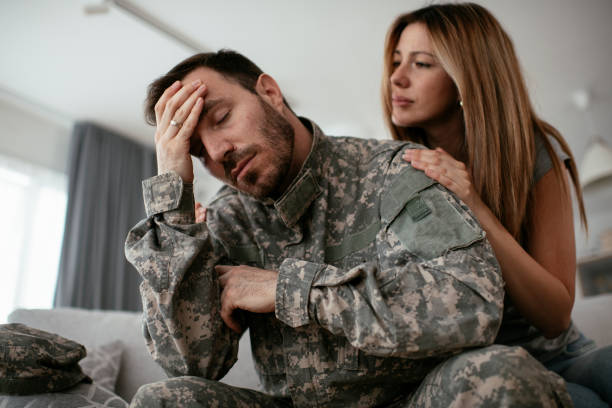 Depressed soldier sitting on sofa with his wife. stock photo