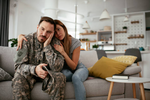 soldato depresso seduto sul divano con sua moglie. - men male military beautiful foto e immagini stock
