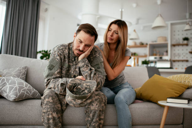 istock Depressed soldier sitting on sofa with his wife. 1285849318