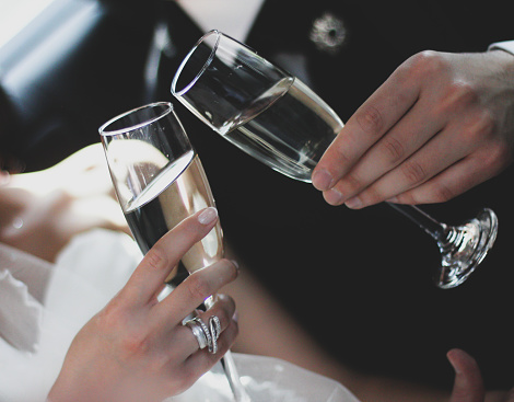 Wedding celebration. Bride and groom holding glasses of champagne making a toast, hands with glasses close up