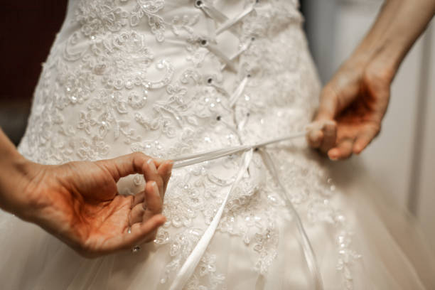 istock Bride buttoning the back of lace wedding dress 1285850413