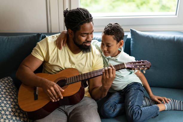 istock Father playing a guitar to his son at home. 1285851334