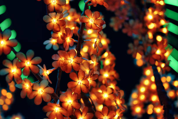 Garland on tree. Colorful light bulbs in the form of flowers. Bright festive lighting of the city. Illumination at night. Winter holiday. Concept of Christmas and New year.