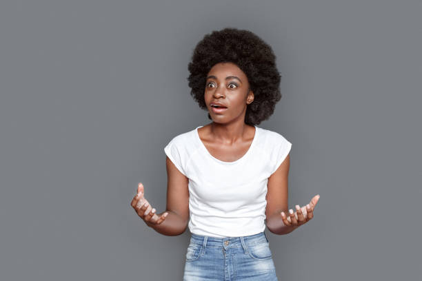 istock Young woman standing isolated on gray hands aside shocked 1285857312